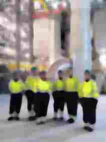 visitors in PPE in front of stacks inside