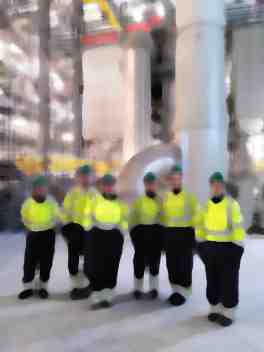 visitors in PPE in front of stacks inside